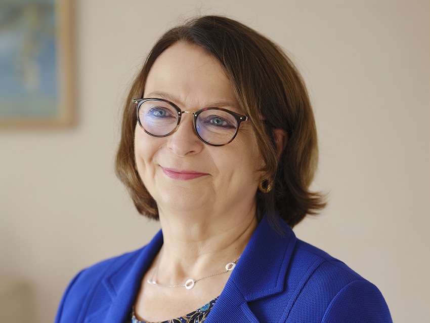 Portrait de Christine Huchette souriante avec un blaser bleu.